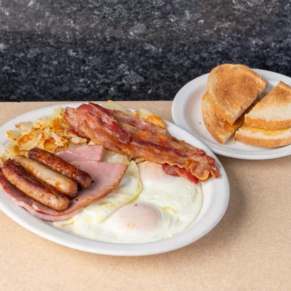 A full American breakfast with bacon, sausage, ham, eggs, hash browns, and toast.